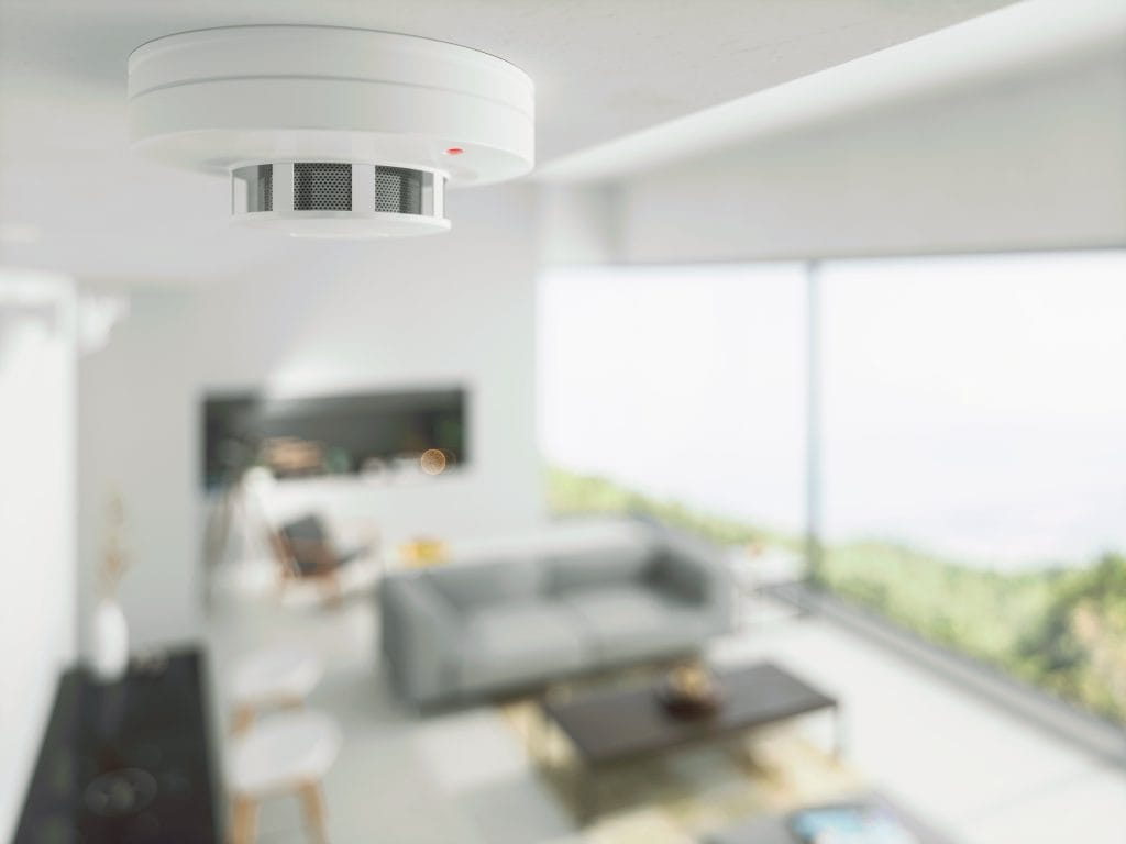 Smoke and heat detector on ceiling of a home's living room 