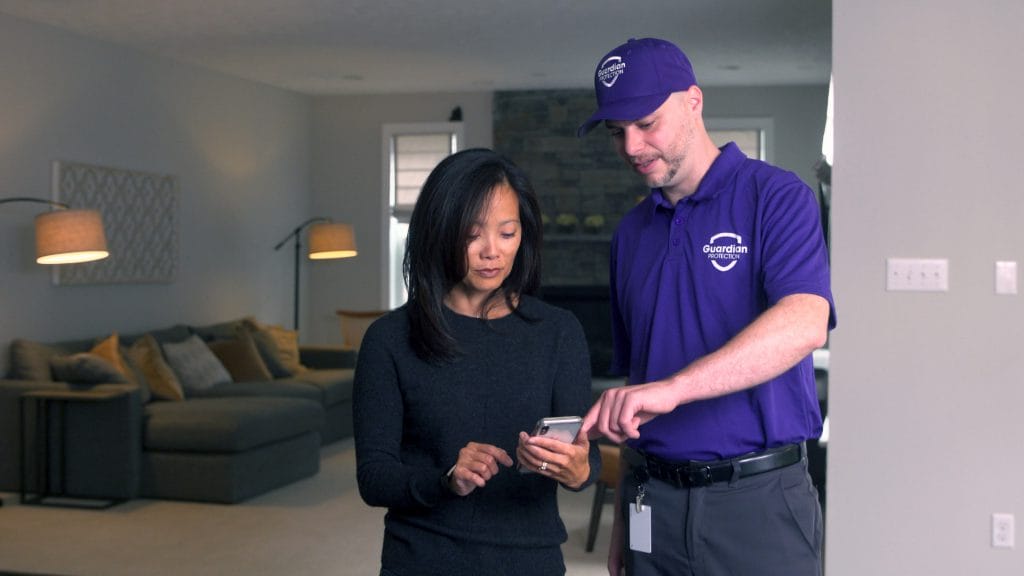 Guardian Protection technician showing customer how to use mobile app to monitor home security devices