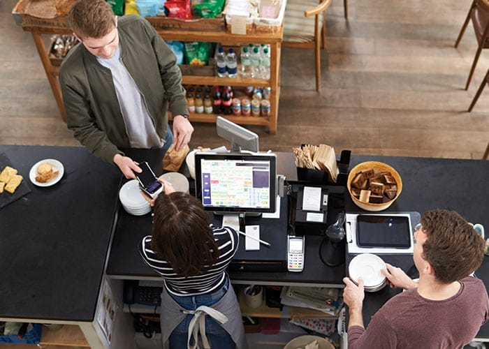 Overhead view of two employees checking out a customer at a restaurant's cash register